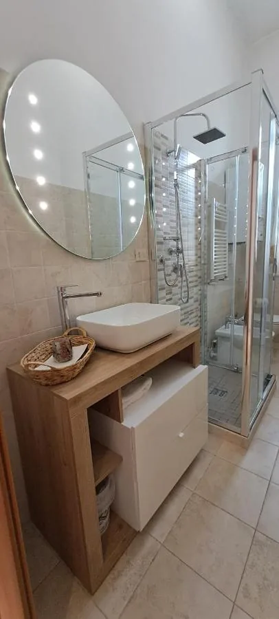 La Dimora del Sole — Il bagno con il lavabo in appoggio, lo specchio rotondo e il box doccia